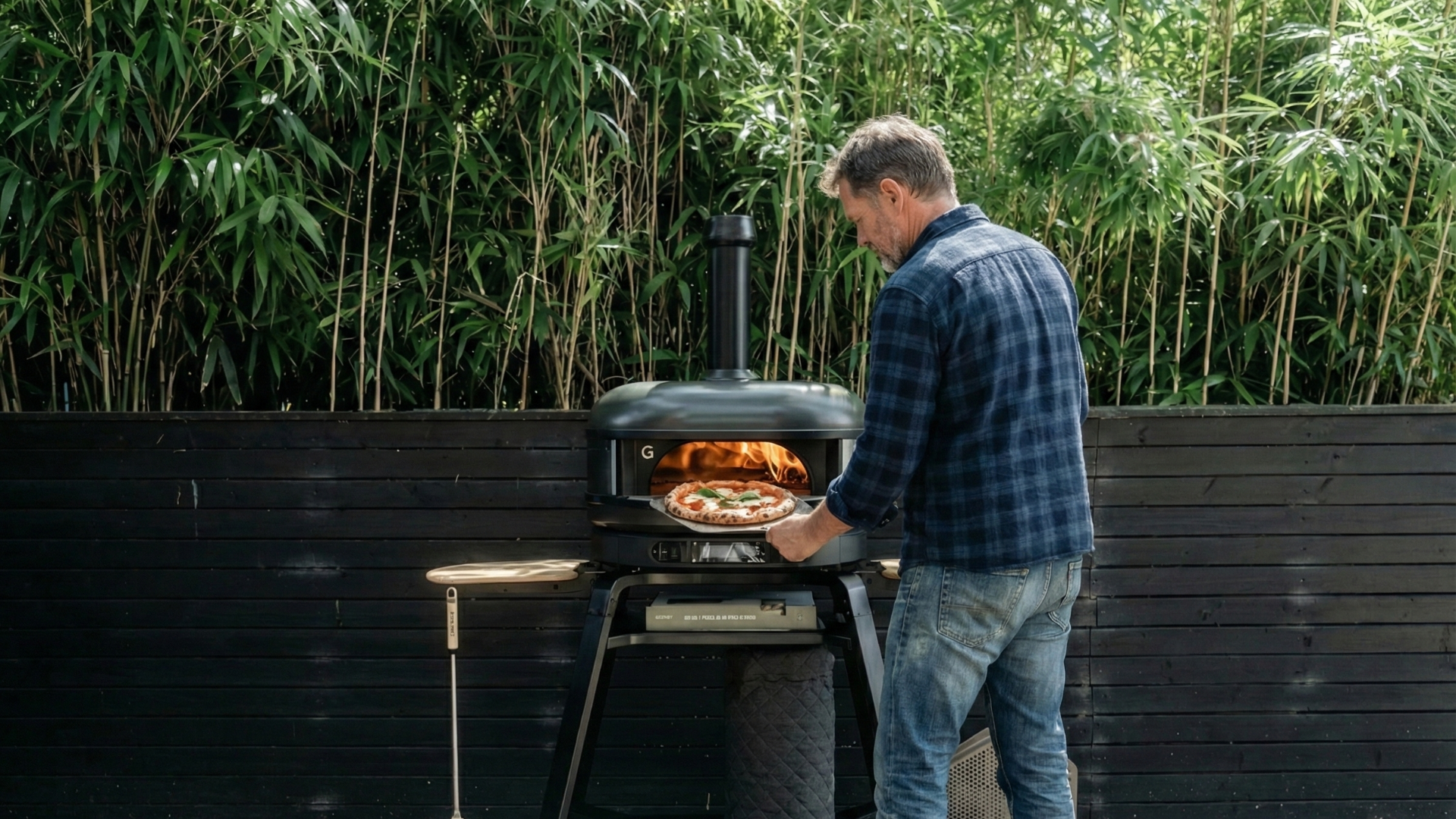 Mann bereitet Pizza in einem Gozney Pizzaofen im Garten zu