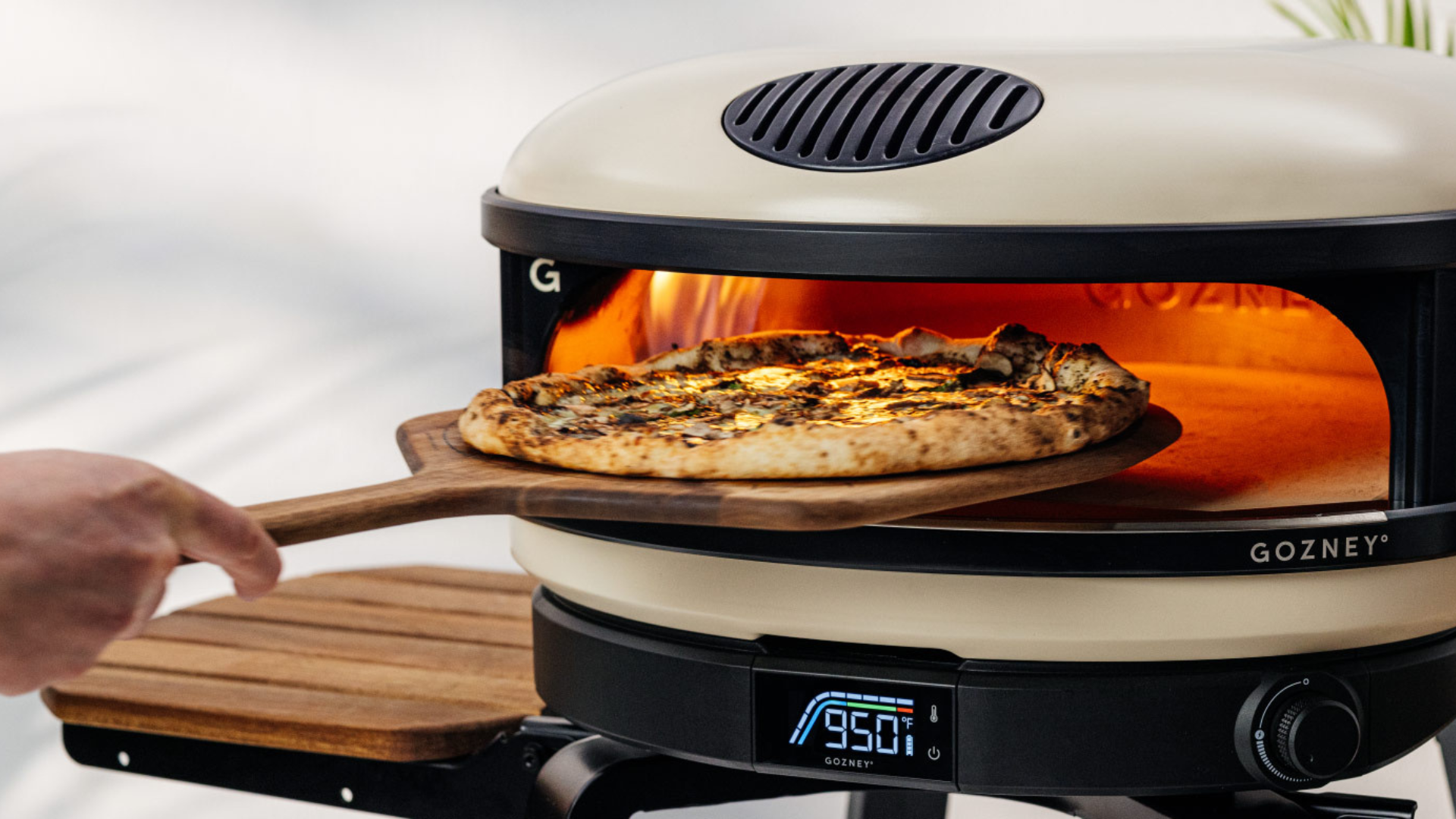 Pizza wird auf einem Holz-Servierbrett aus einem Gozney Pizzaofen genommen