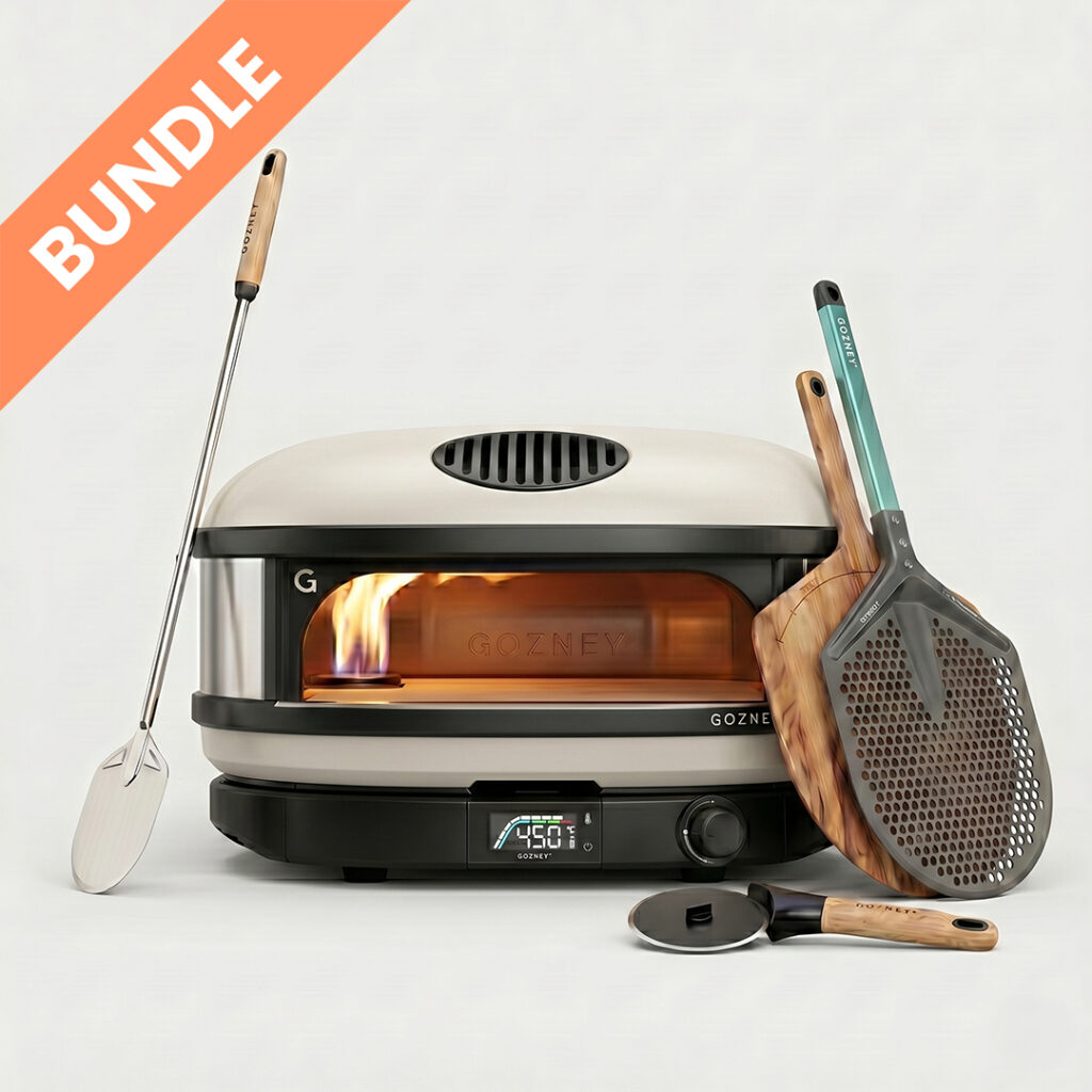 Gozney Arc XL Creme Pronto Starter Set Bundle – Großer Pizzaofen Nahaufnahme liegend mit sichtbarer Flamme, Metallschaufel, Holzpeeler und Pizzaschneider